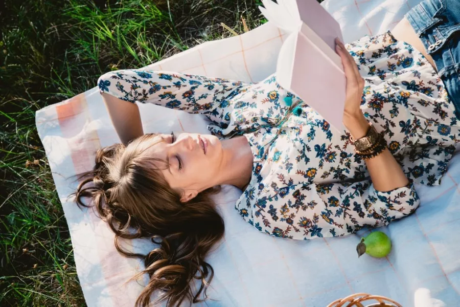 Une femme allongée dans l’herbe lit un livre