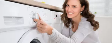Une femme programme son lave-linge 