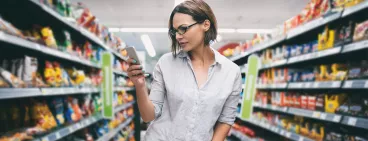 Une femme regardant son smartphone faisant les courses