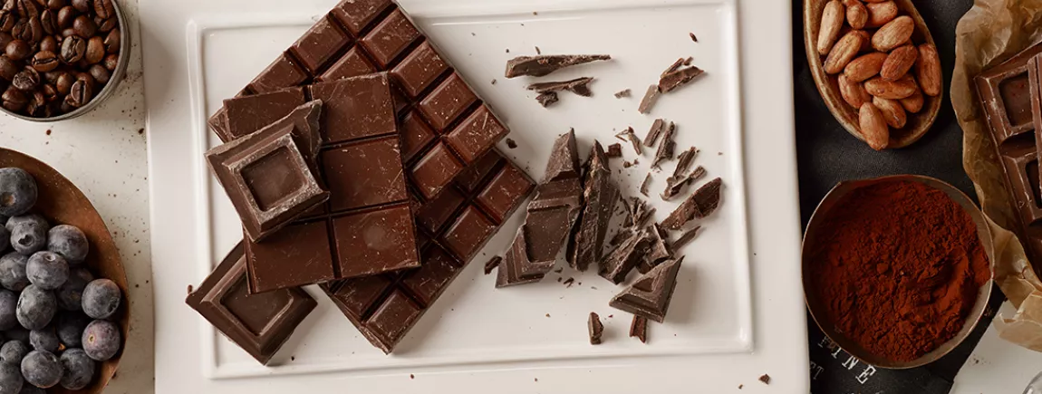 Une femme croque dans un carré de chocolat