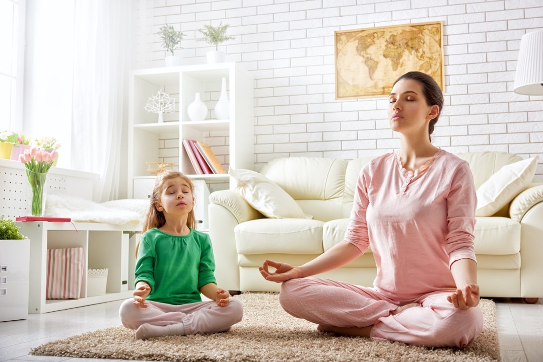 Une mère et sa fille en pleine méditation dans leur salon