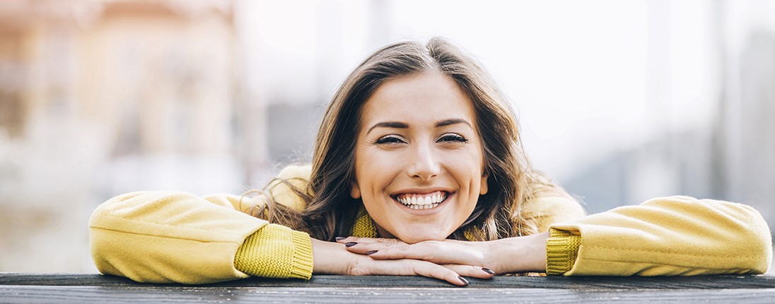 Une femme souriante appuyée sur un balcon