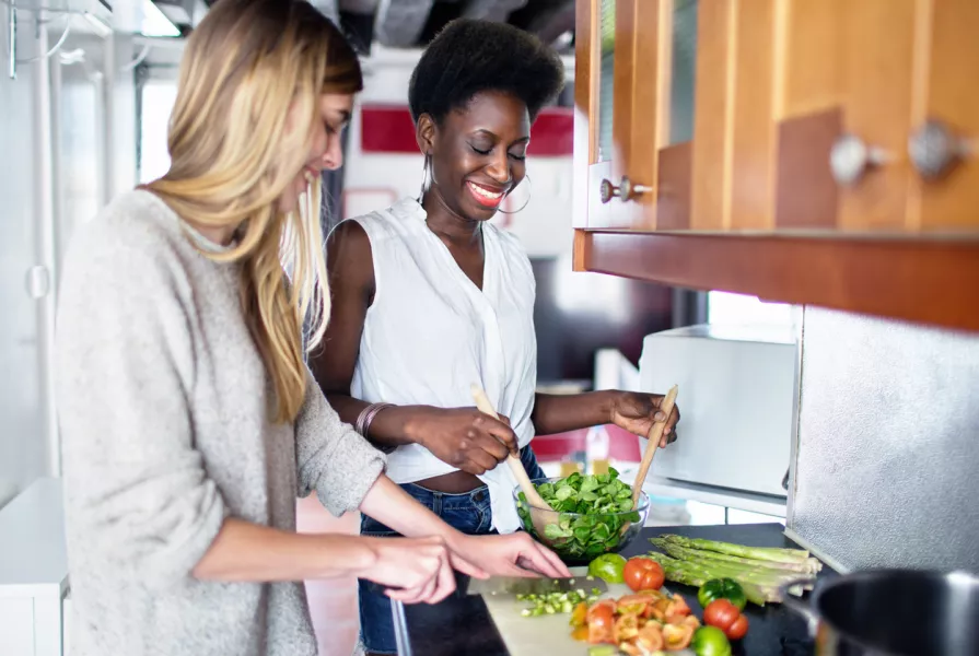 Deux femmes cuisinent des légumes. 