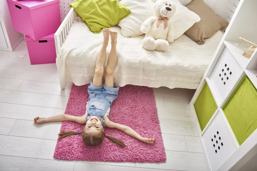 Une petite fille joue sur le sol de sa chambre.