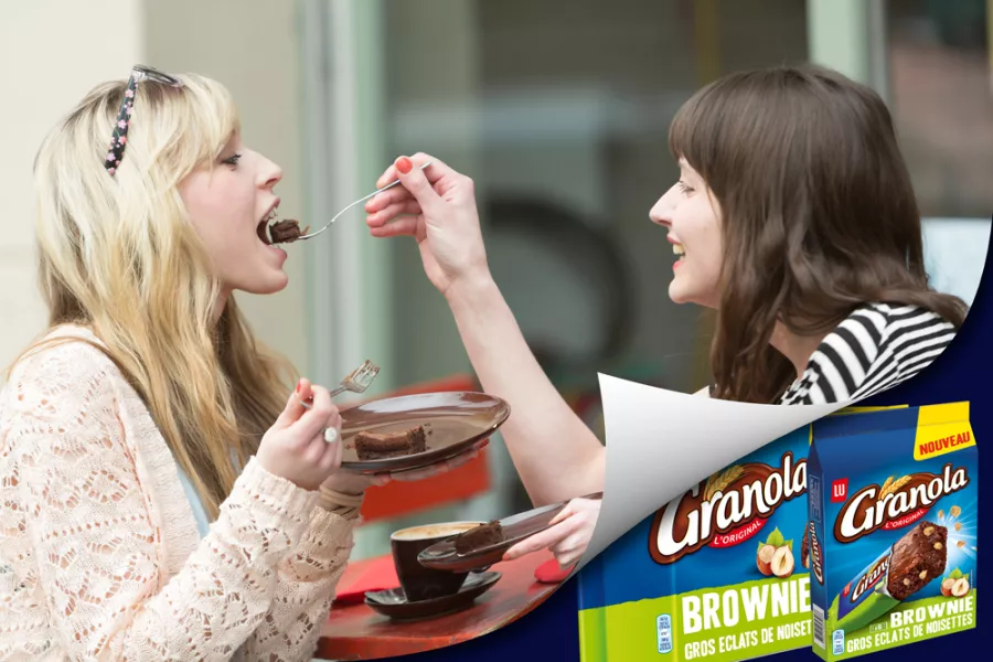 Deux amies se font goûter un brownie dans un café.