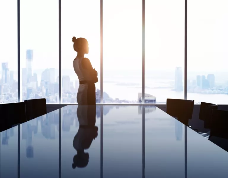 Une femme regarde un panorama du haut d’un bureau situé dans un building