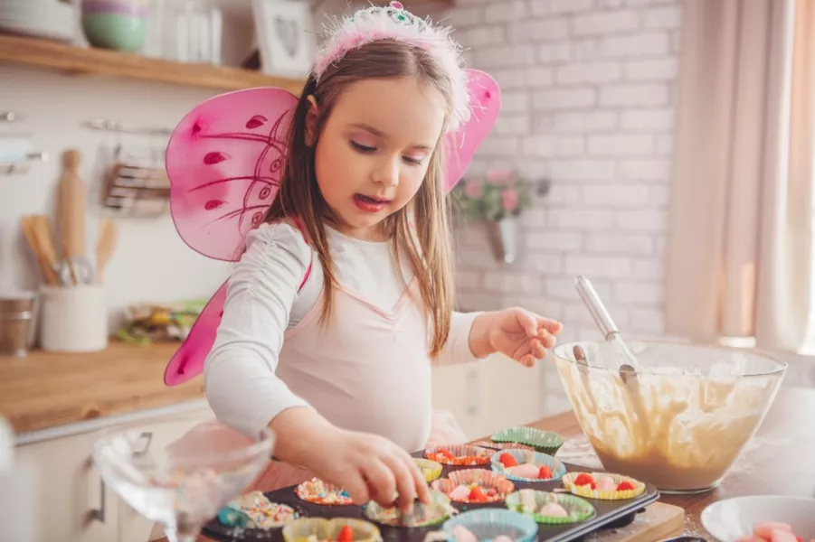 Une petite fille cuisine des cupcakes