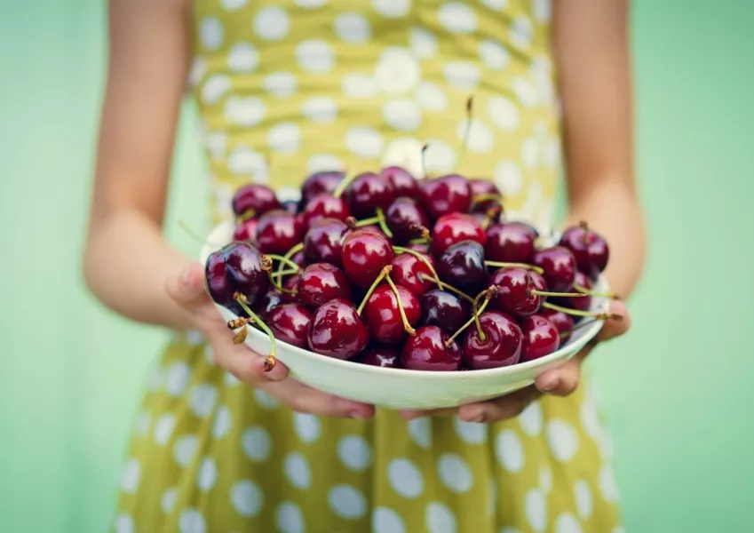 Une femme apporte un plat de cerises