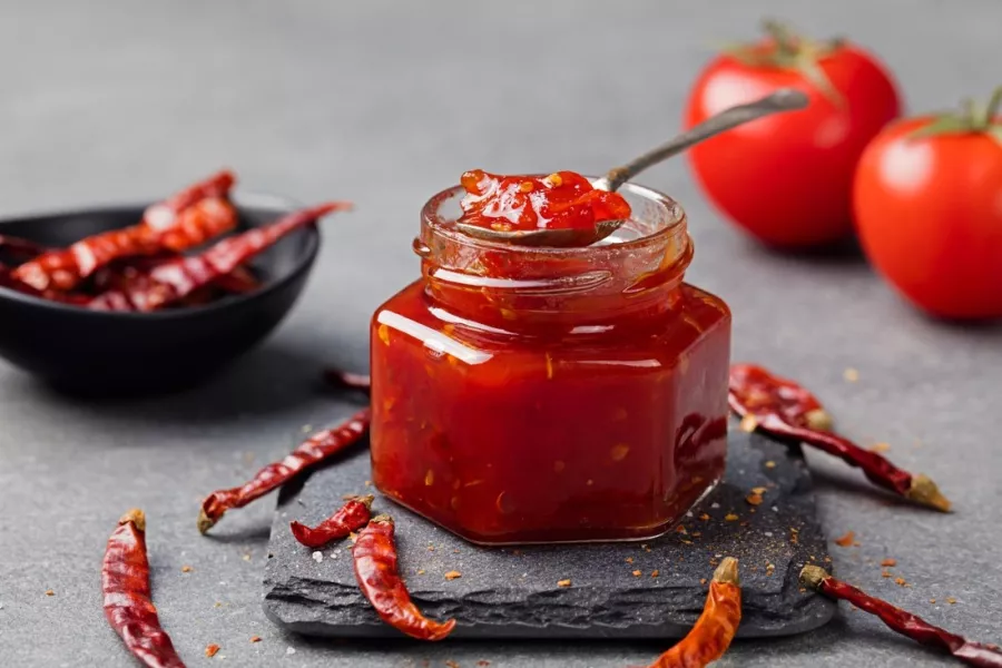 Un pot de confiture de tomates et piments disposé sur une table