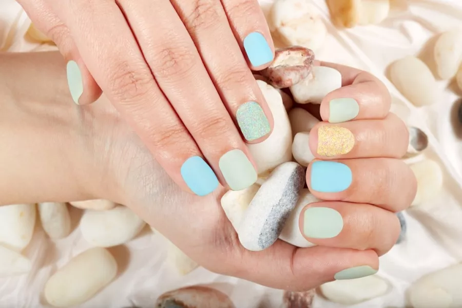 Des mains de femme aux ongles vernis bleu pastel