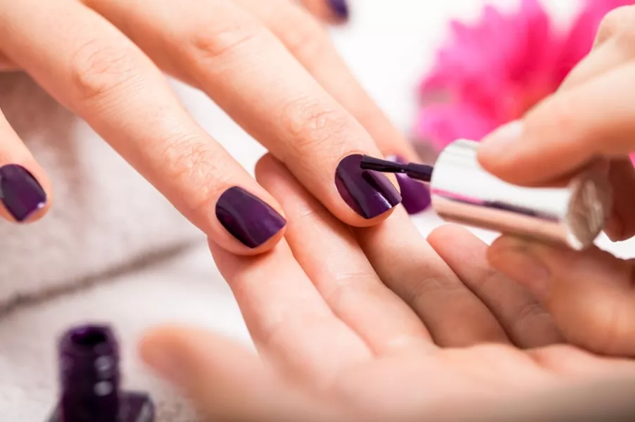 Des mains de femme aux ongles vernis violet brillant