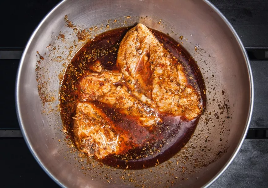 Un poulet mariné dans un récipient