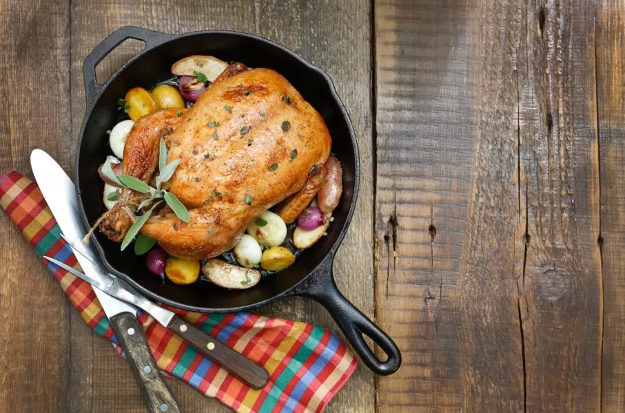 Une casserole contenant un poulet et des légumes sur une table