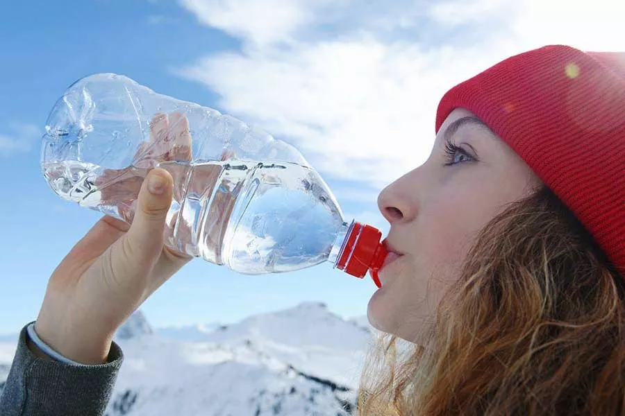 Une femme fait une pause dans sa journée de ski pour s’hydrater.