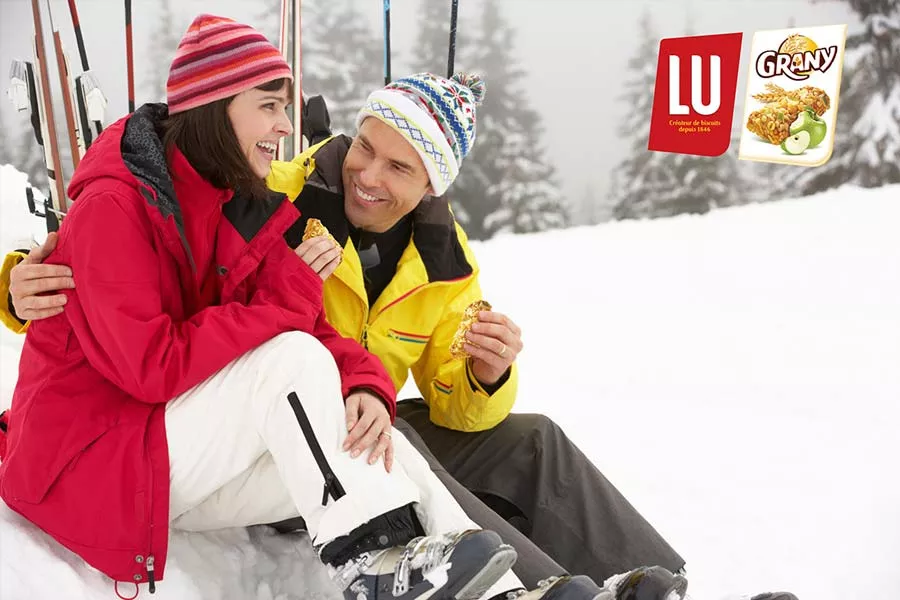 Un couple fait une pause collation au ski.