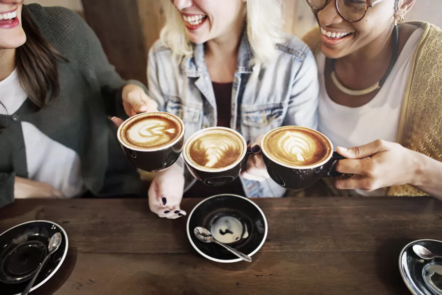 Un groupe d’amies s’apprennent à déguster un café en trinquant avec leurs tasses