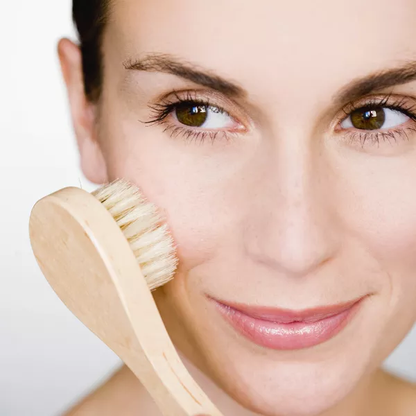 Femme qui se nettoie le visage avec une brosse naturelle