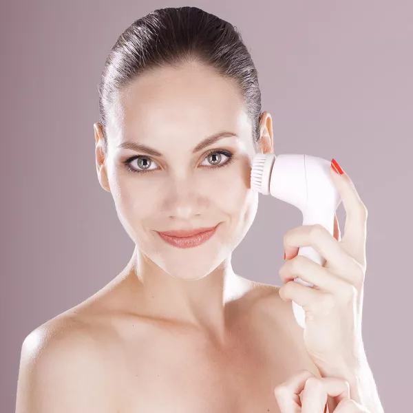 Femme qui se nettoie la peau avec une brosse électrique