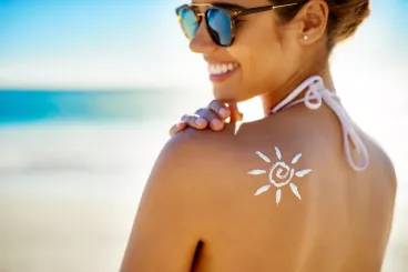 Une femme se passe de la crème solaire dans le dos