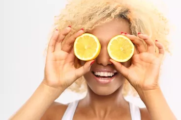 Une femme se cache les yeux avec deux moitiés de citron