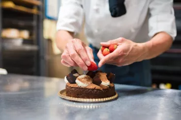 Un chef patissier élabore un gâteau au chocolat et aux fraises