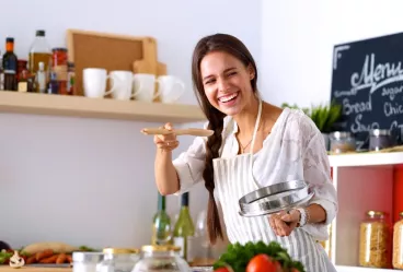 Une femme fait la cuisine en souriant