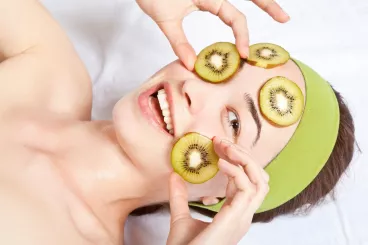 Une femme dispose des tranches de kiwi sur son visage