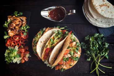 Des tacos au poulet, des poivrons, des tomates, du basilic, et de la sauce Barbecue Amora.