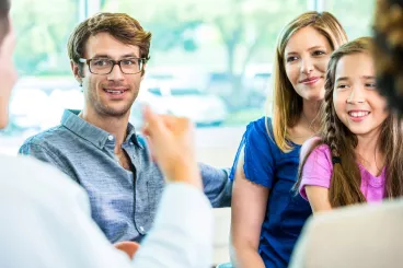 Des parents et leur fille à une réunion parents-profs