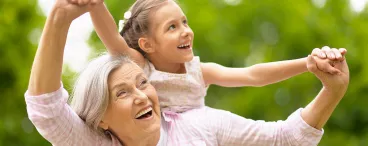 Une grand-mère et sa petite fille sur son dos qui passent un bon moment dans un espace extérieur 