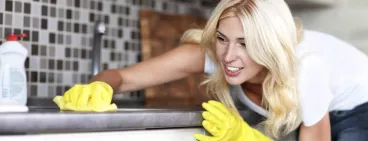 Une femme nettoye sa cuisine avec un produit d’entretien.