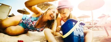 Une mère et sa fille jouent avec du sable sur une plage