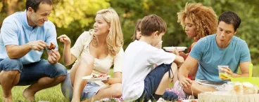 Idées gastronomiques pour un pique-nique 100% pratique Un groupe de gens partagent un pique-nique dans un parc.
