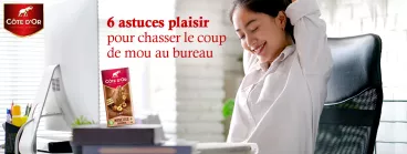 Une femme heureuse au bureau qui mange du chocolat