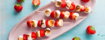 Brochettes de fraises et guimauves grillées sur un plat