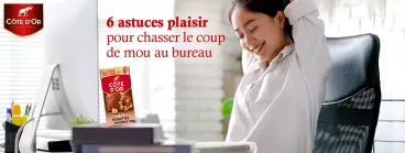 Une femme heureuse au bureau qui mange du chocolat