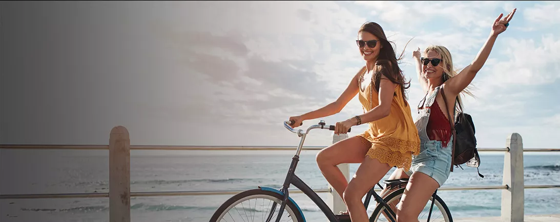 Deux filles faisant du vélo en bord de mer.