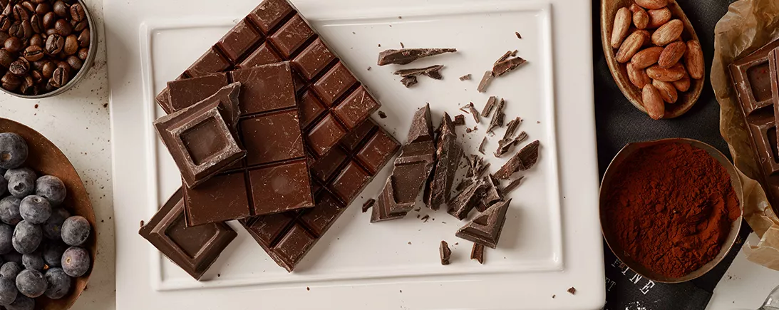 Une femme croque dans un carré de chocolat