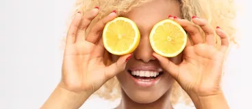 Une femme se cache les yeux avec deux moitiés de citron
