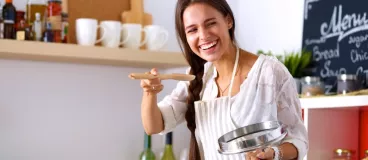 Une femme fait la cuisine en souriant