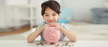 Un enfant range son argent de poche dans sa tirelire.