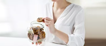 Une femme mange des cookies rangés dans un bocal