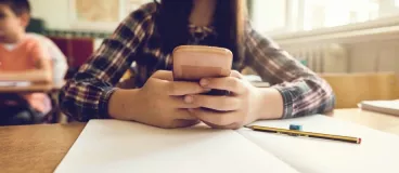 Plus de portables dans la classe ! Une jeune élève qui utilise son portable en classe