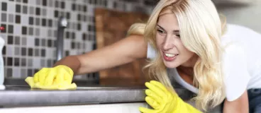 Cuisine : la chasse aux bactéries est ouverte ! Une femme nettoye sa cuisine avec un produit d’entretien.