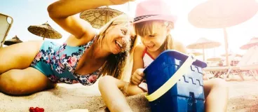 Une mère et sa fille jouent avec du sable sur une plage