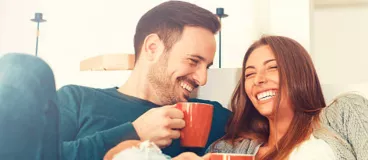 Un couple rigole en buvant un café
