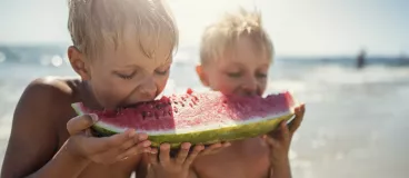 enfants à la plage mangeant une pastèque