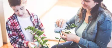 Une mère et son fils entretiennent une plante.