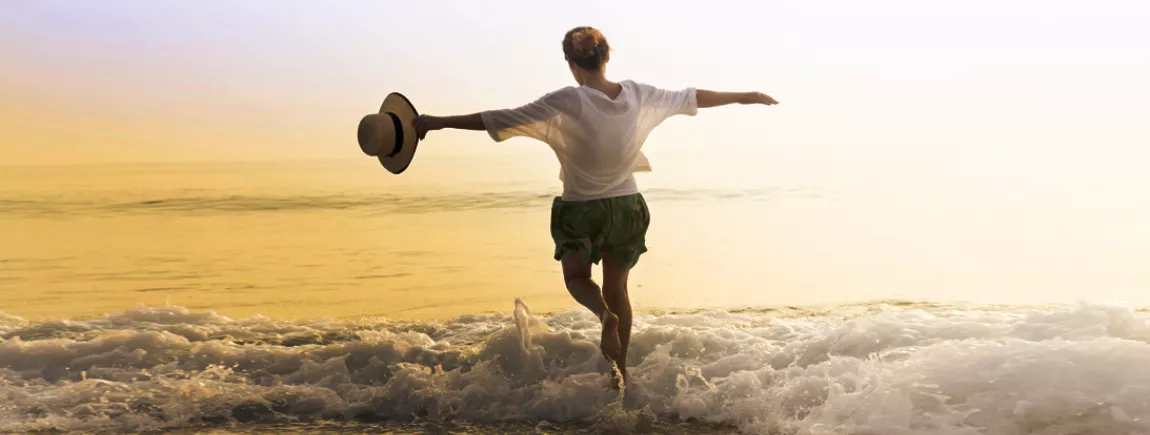 Une femme joue avec les vagues au bord de la mer