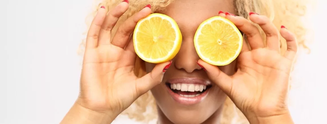 Une femme se cache les yeux avec deux moitiés de citron